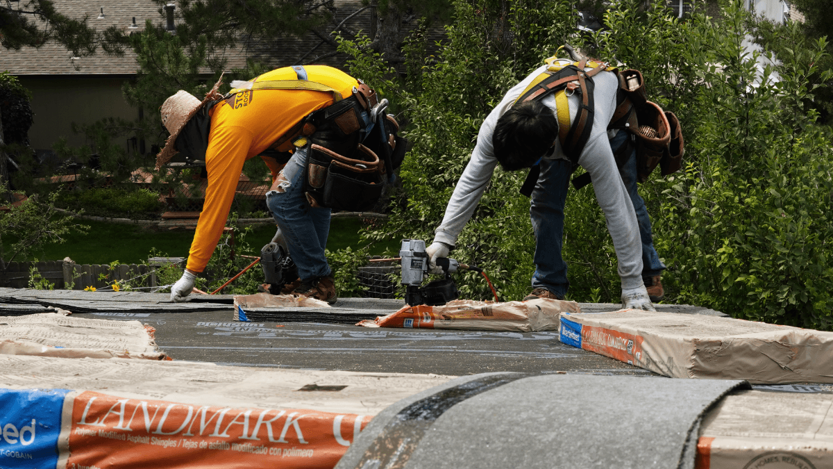 Two roofers nailing in shingles