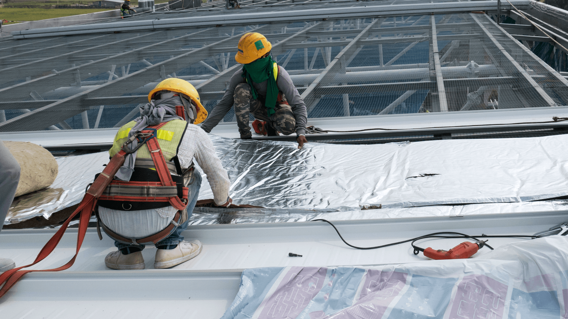 Commercial roofers working on steel roof on stadium